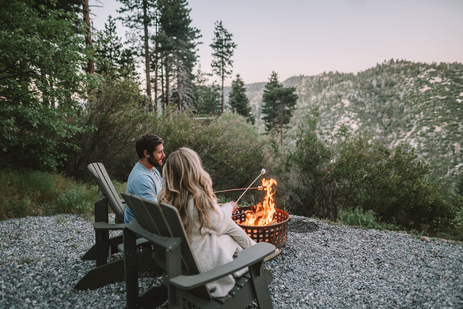 Pareja junto al fuego asando malvaviscos en Getaway House en Big Bear