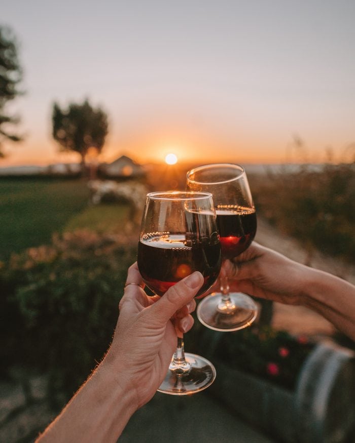 Dos copas de vino tinto tintineando al atardecer
